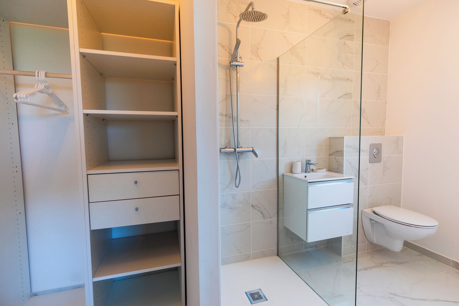 A modern bathroom with a glass shower enclosure, a toilet, and a vanity with a mirror.