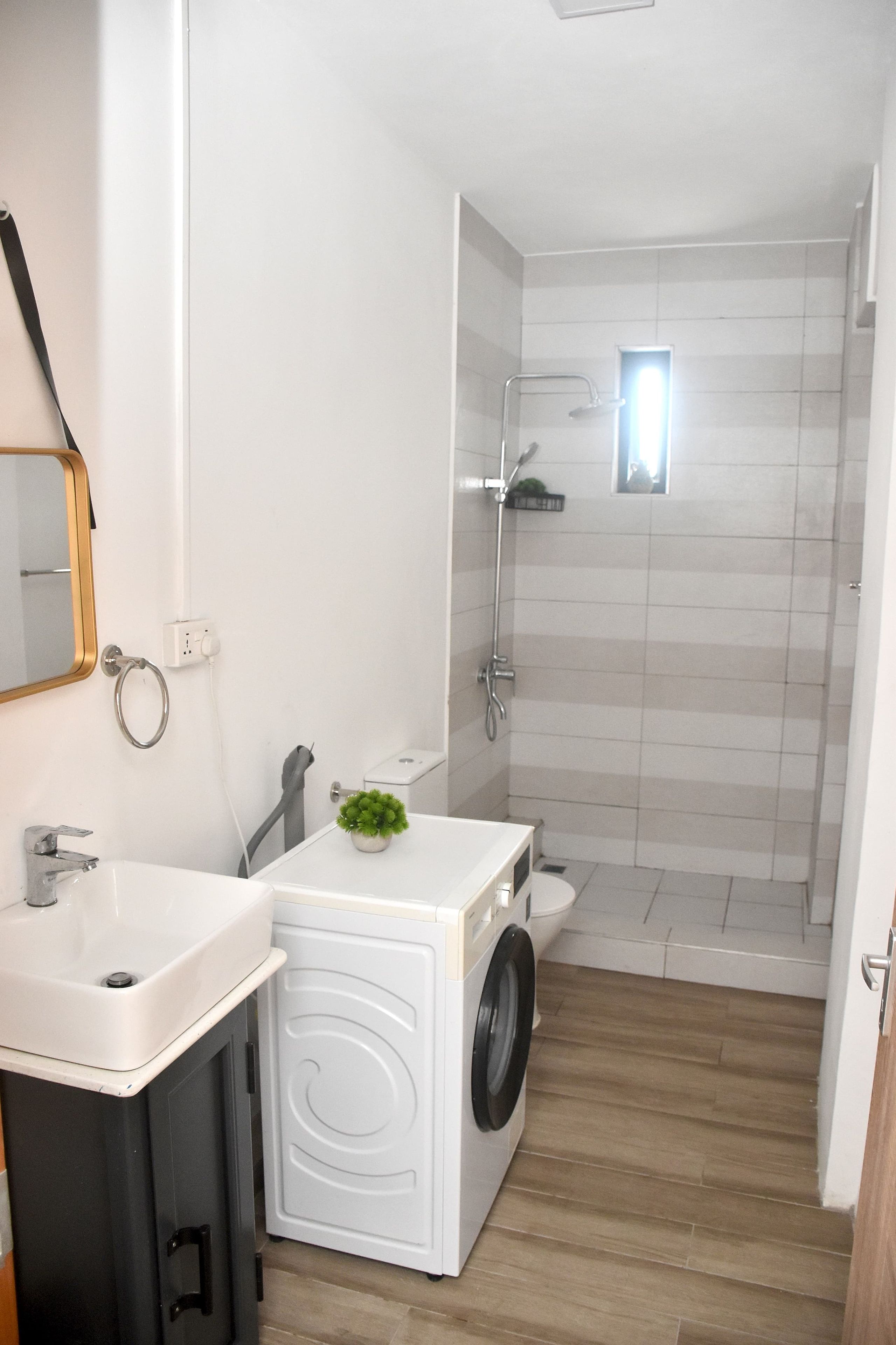 Un bagno compatto con lavandino, specchio, toilette e una piccola lavatrice.