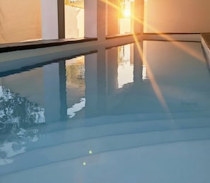 A pool with clear water reflecting sunlight, surrounded by a white structure.