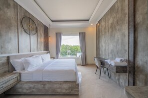 A modern hotel room with a large bed, a desk, and a view of the outdoors. - Gorgeous 8-bedroom house with great facilities. (Bali)
