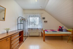 A bedroom with a wooden bed, a dresser, a mirror, and a window with curtains.