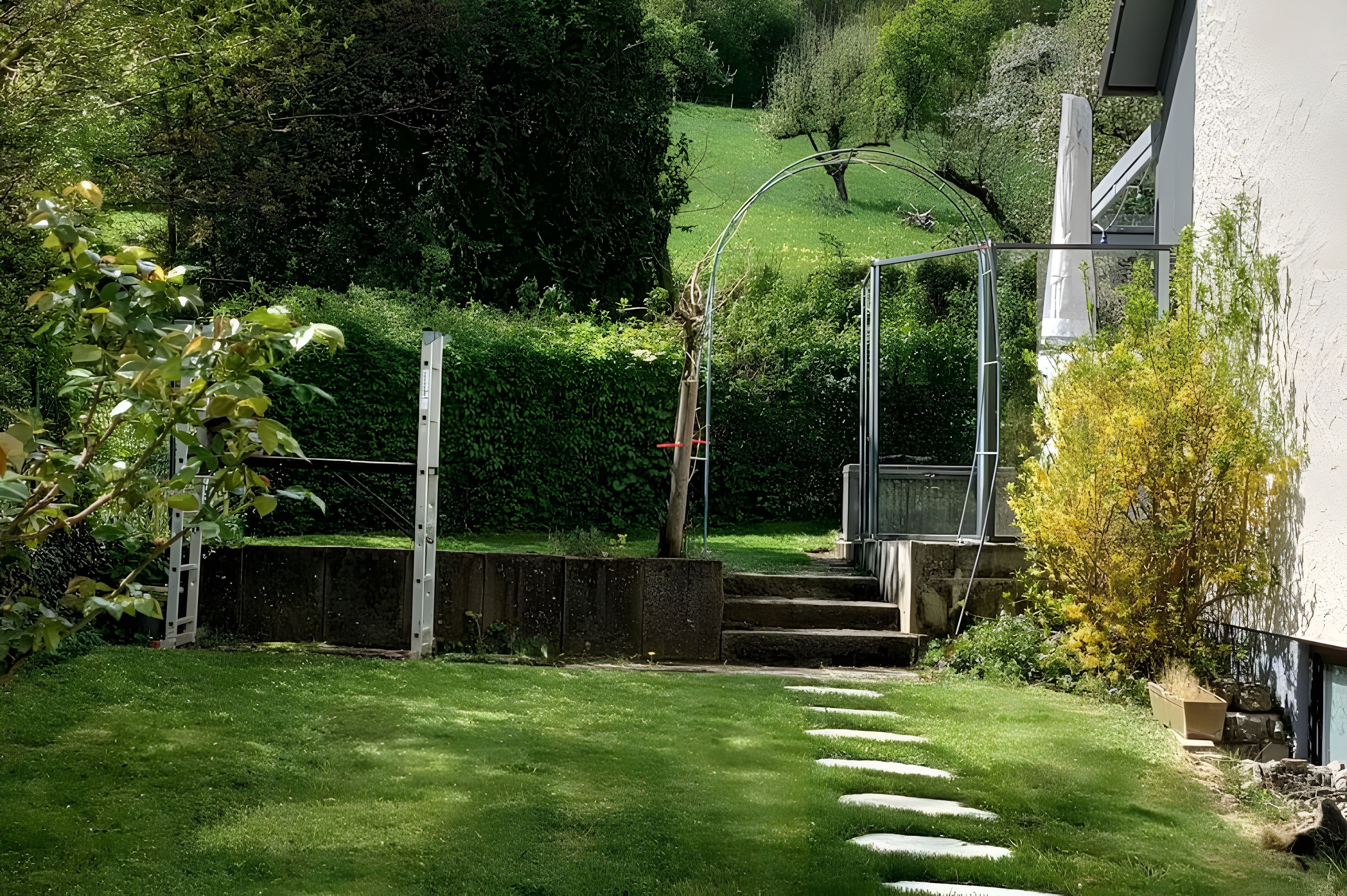 Un jardin avec un sentier de pierres menant à un escalier en bois.