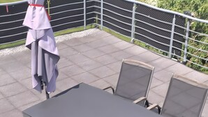 Eine Terrasse mit Tisch und Stühlen, einem Geländer und Blick ins Grüne.
