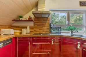 A modern kitchen with wooden cabinetry, a built-in oven, and a window providing a view of greenery outside.