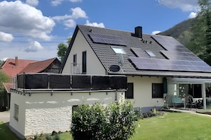 A modern house with a sloped roof, solar panels, and a glass door leading to a patio. - Apartment in Green Setting by Rosenstein with Mountain View, Private Terrace, and Wi-Fi (Heubach)