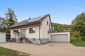 Ein zweistöckiges Haus mit Garage und einer gepflasterten Auffahrt, sowie einer Treppe, die zu der oberen Etage führt.