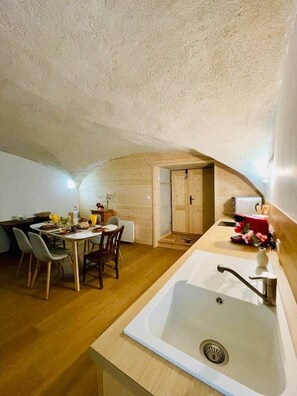A compact kitchen with a sink, wooden cabinets, and a dining area with chairs and a table. - At Toutoune - Mountain Retreat - Sleeps 6, Aussois (Aussois)