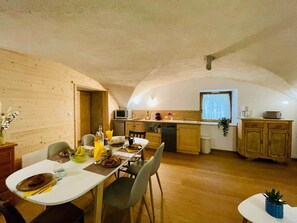 A compact kitchen with wooden cabinets, a dining table with chairs, and a small window. - At Toutoune - Mountain Retreat - Sleeps 6, Aussois (Aussois)