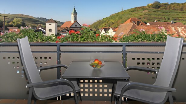 En terrasse med to stole, et bord og en skål med frugt.
