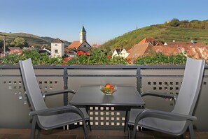 En terrasse med to stole, et bord og en skål med frugt.