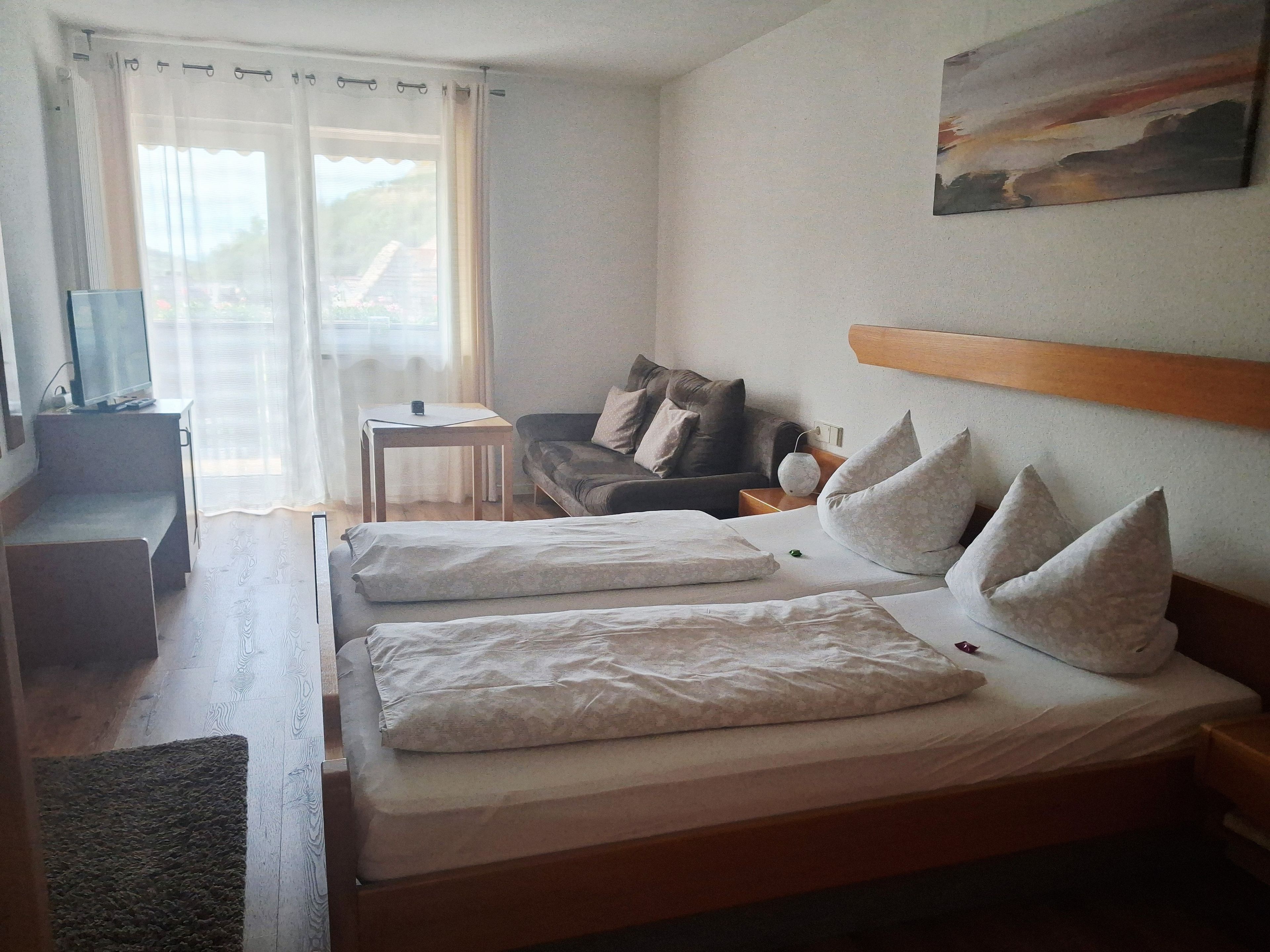 Une chambre d’hôtel avec un lit, un canapé, une télévision et un tableau au mur.