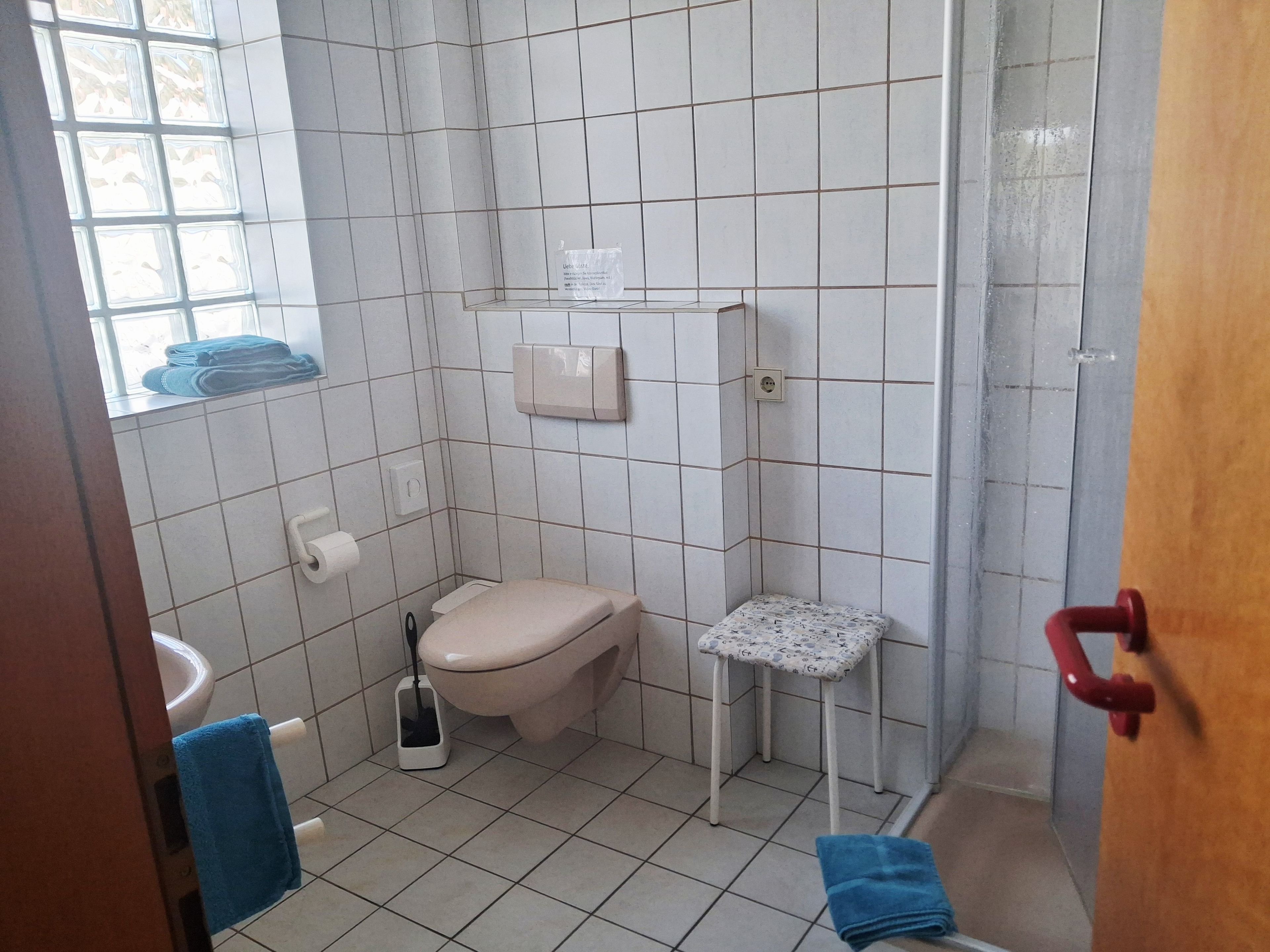 Um banheiro pequeno com vaso sanitário, pia, chuveiro e porta-toalhas.