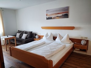 Ein Hotelzimmer mit einem Holzbett, einer Couch, einem kleinen Tisch und einem Bild an der Wand.