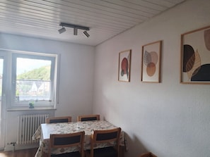 Ein Essbereich mit Tisch und Stühlen, einem Fenster mit Blick und drei gerahmten Kunstwerken an der Wand.