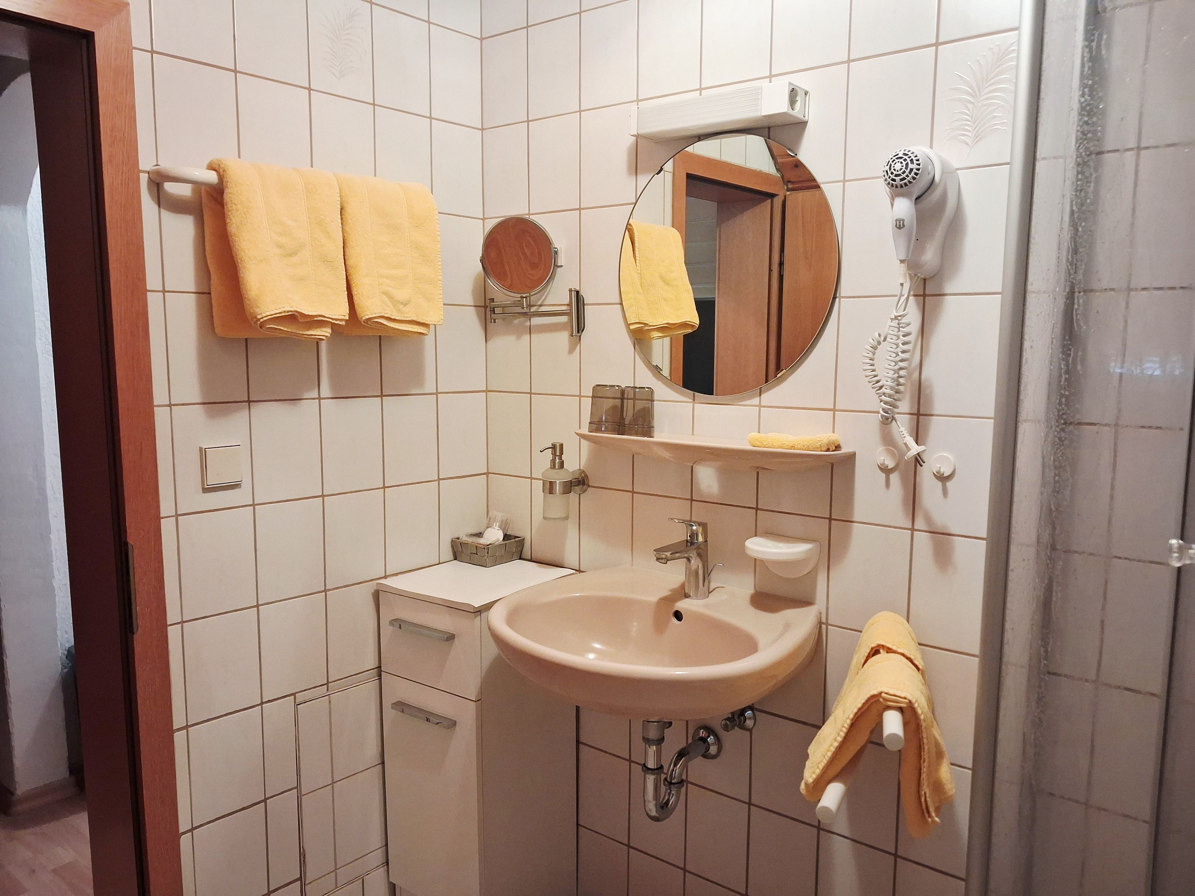 Ein Badezimmer mit Waschbecken, Spiegel, Handtuchhalter und einem Fön.