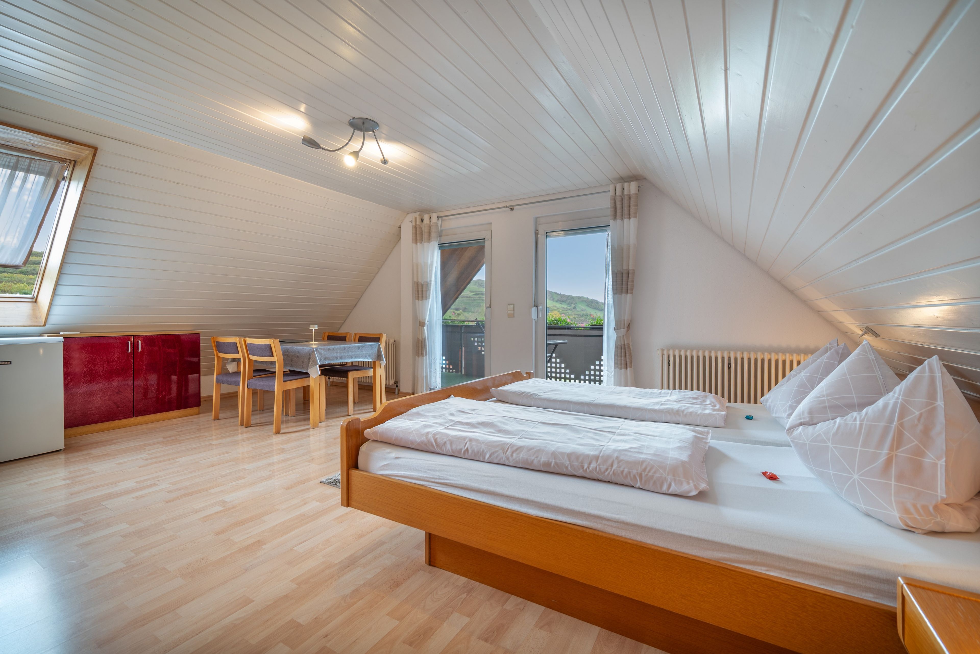 Ein Schlafzimmer mit einem hölzernen Bett, einem kleinen Tisch und Stühlen.