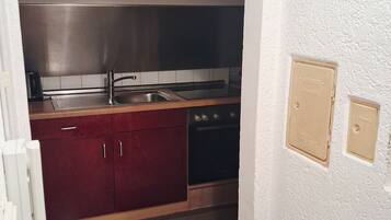 Cozinha compacta com exaustor de aço inoxidável, forno embutido e máquina de lavar louça.