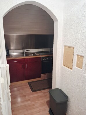 A compact kitchen with a stainless steel range hood, a built-in oven, and a dishwasher.