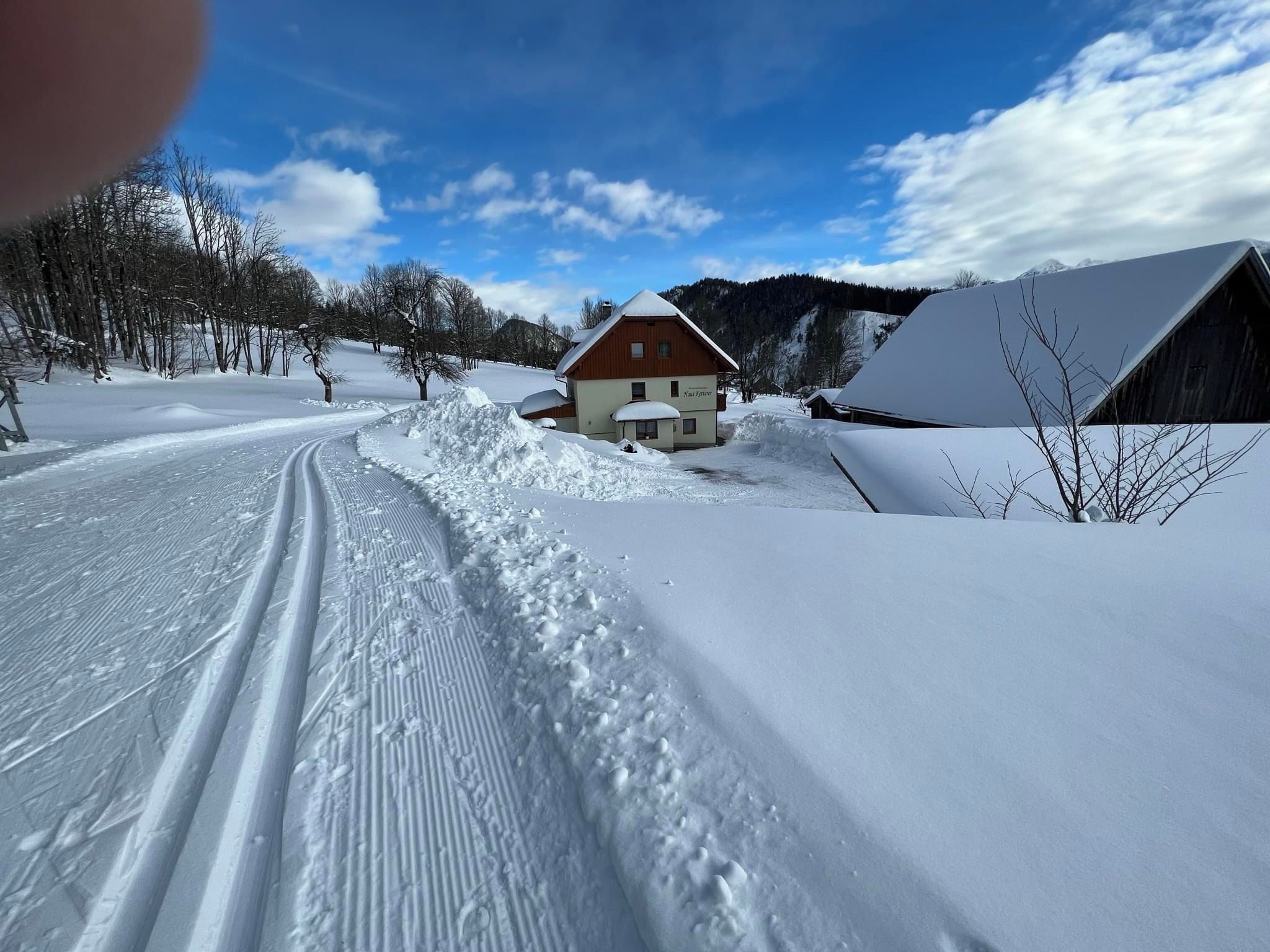 Schneebedeckte Landschaft mit einem Holzhaus und einer Scheune.