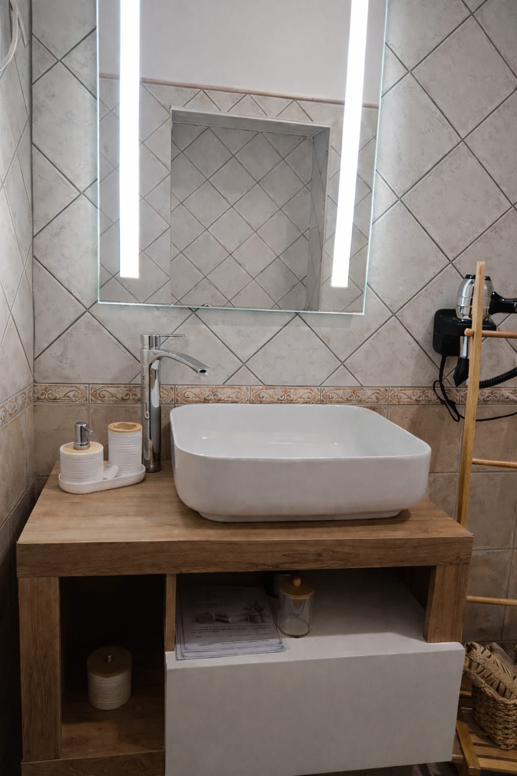 Un baño con un lavamanos blanco rectangular, un espejo encima y un mueble de tocador de madera.