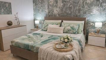 Ein Schlafzimmer mit einem Bett, Nachttischen, einer Lampe, einer dekorativen Vase und einem Tablett mit Tasse und Keksen.