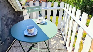 Een balkon met een tafel en twee kopjes, met uitzicht op een dorp met huizen en groen.