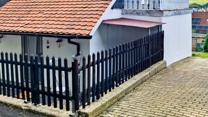 Een huis met een rode pannendak, een witte gevel en een zwarte omheining.