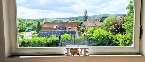 Una habitación con un amplio ventanal que da a una zona residencial con paneles solares en los tejados.
