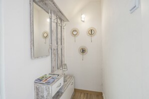 A bathroom with a wooden vanity, a mirror, and wall-mounted lights.