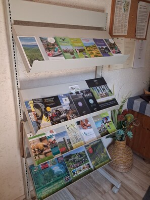 A display of brochures and informational booklets on a shelf, with a bulletin board in the background.