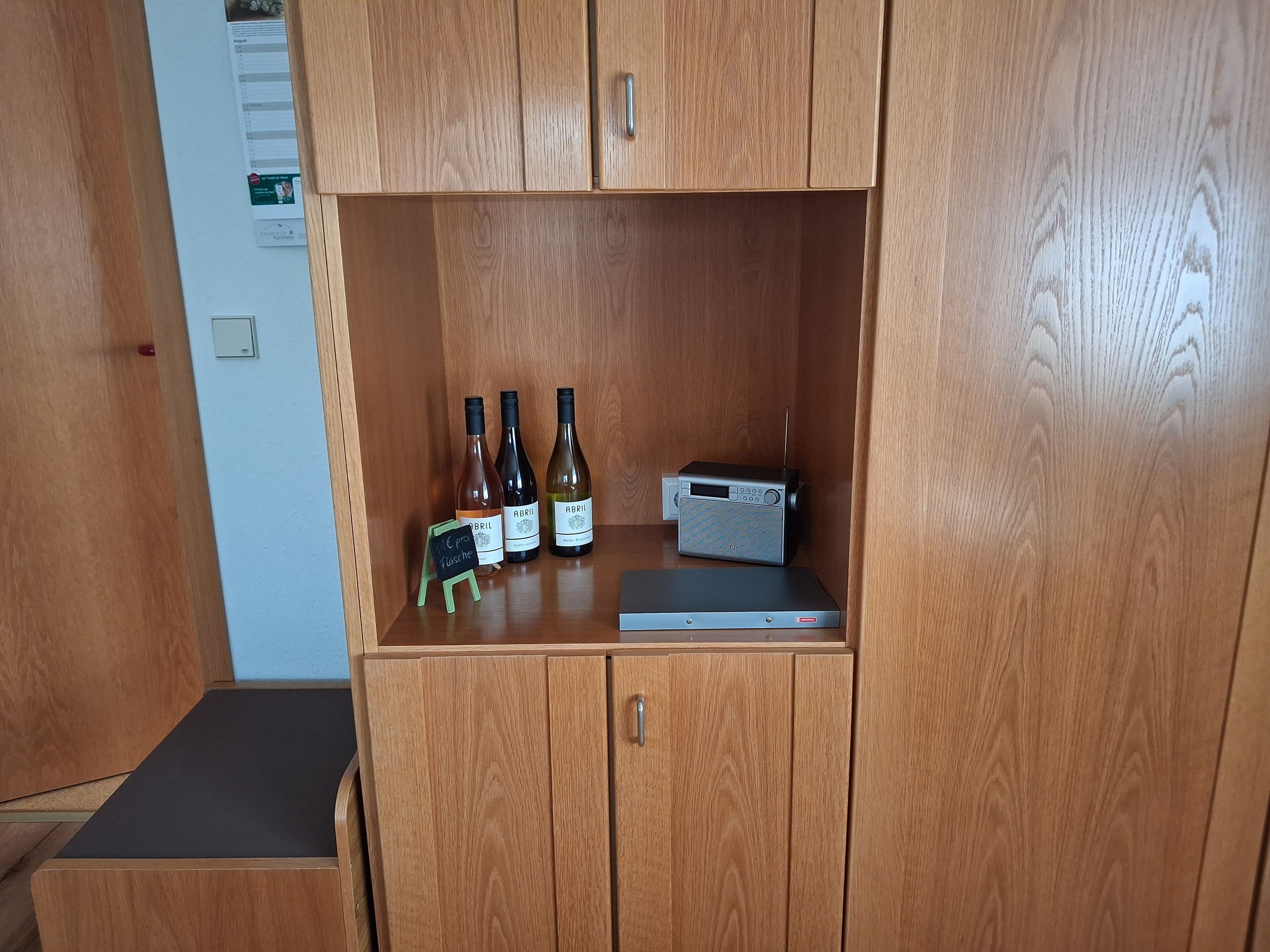 Ein Holzkabinet mit drei Weinflaschen und einem Radio.