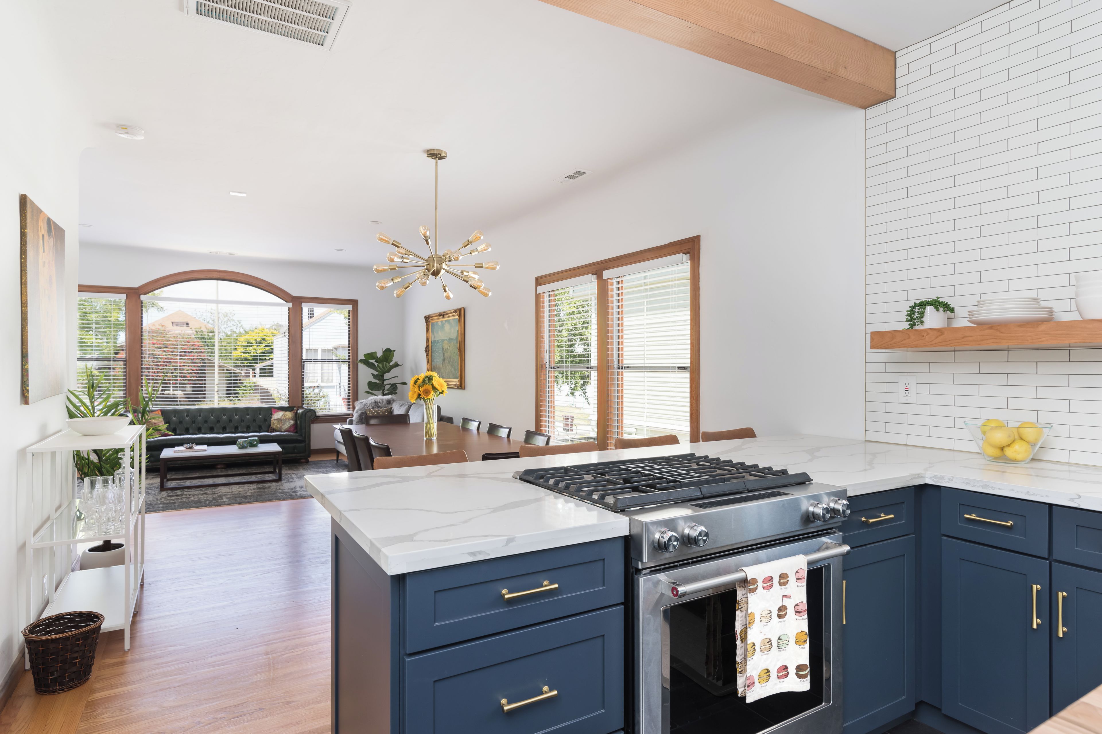 A modern kitchen with dark blue cabinets, a white marble countertop, and a stainless steel stove.
