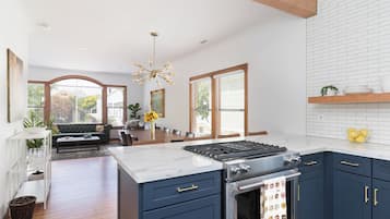 A modern kitchen with dark blue cabinets, a white marble countertop, and a stainless steel stove.