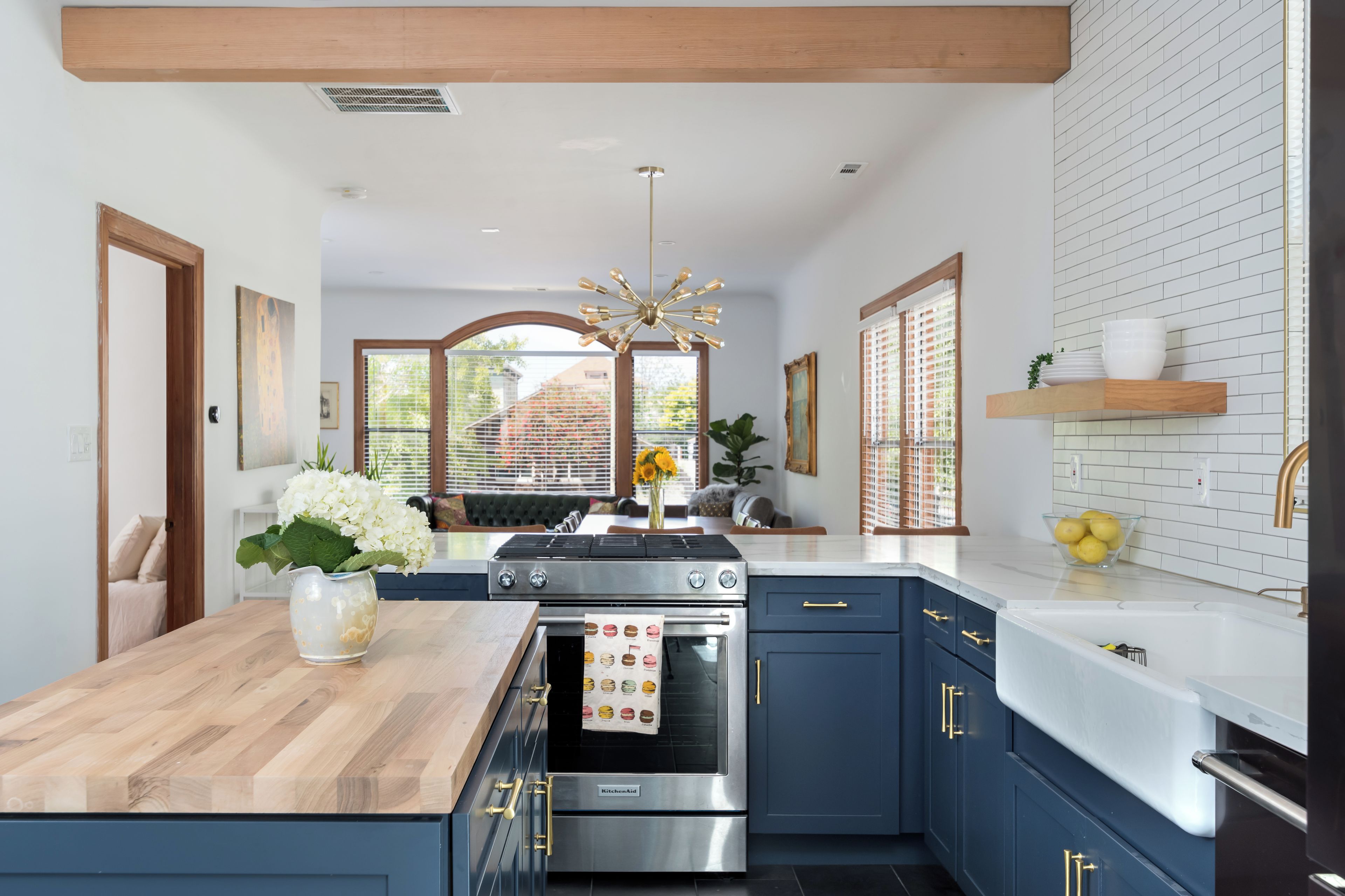 Una cocina moderna con una isla central, horno empotrado y muebles azules.