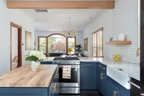 Una cocina moderna con una isla central, horno integrado y armarios azules.