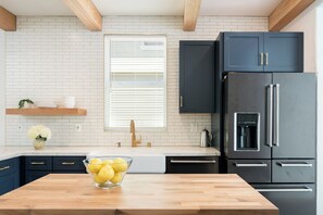 Una cocina moderna con armarios oscuros, un refrigerador de acero inoxidable y una encimera de madera.