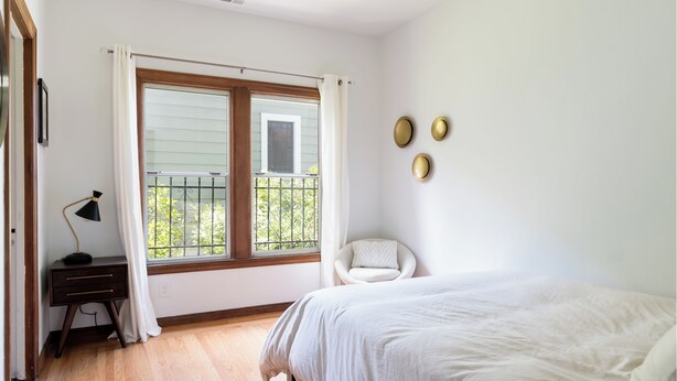 A bedroom with a large window, a bed, a chair, and a desk. - Stunning Two Bedroom Mediterranean Home  (Oakland)