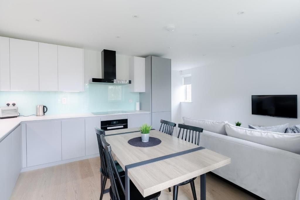 Una cocina moderna con armarios blancos, una mesa de comedor de madera y un sofá blanco.