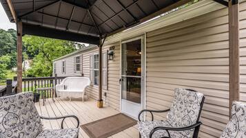 A covered porch with two chairs, a small table, and a door leading to a garage.