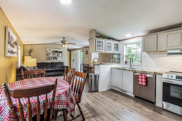 A compact kitchen with white cabinets, a stainless steel refrigerator, and a gas stove. - Tango Spring (Cranberry Township)
