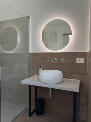 A bathroom with a white sink, a round mirror, and a towel rack. - Piano Peri Stay Inn Nature (Cinisi)