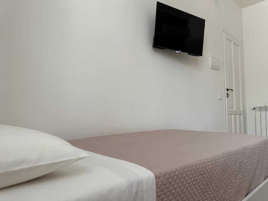 Una habitación con una cama, un televisor de pantalla plana en la pared y una puerta.