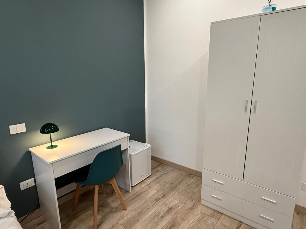 Una habitación con un escritorio blanco, una silla, un armario y un pequeño mueble blanco.