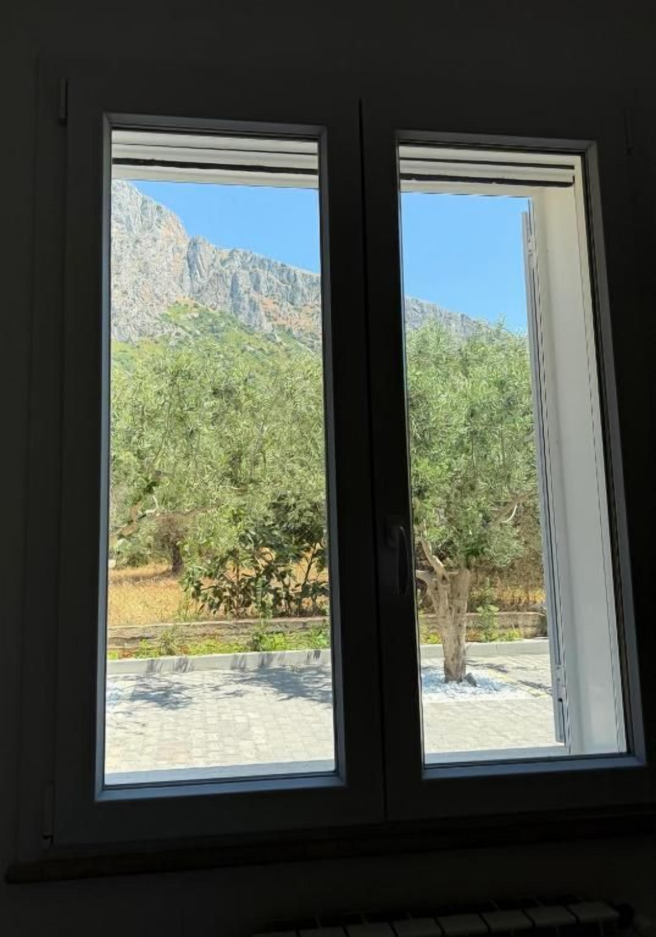 Una ventana con vista a un paisaje montañoso y árboles.