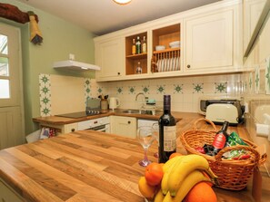 A kitchen with wooden countertops, a toaster, and a bottle of wine. - Corner Cottage (Ulverston)