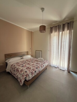 A bedroom with a bed, a bedside table, a radiator, and a window with curtains. - Quaint 2-bedroom apartment with AC in charming Bari (Bari)