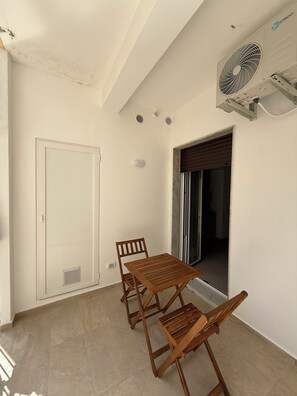 A room with a white door, a wooden table and chairs, a ceiling fan, and a window with blinds. - Quaint 2-bedroom apartment with AC in charming Bari (Bari)