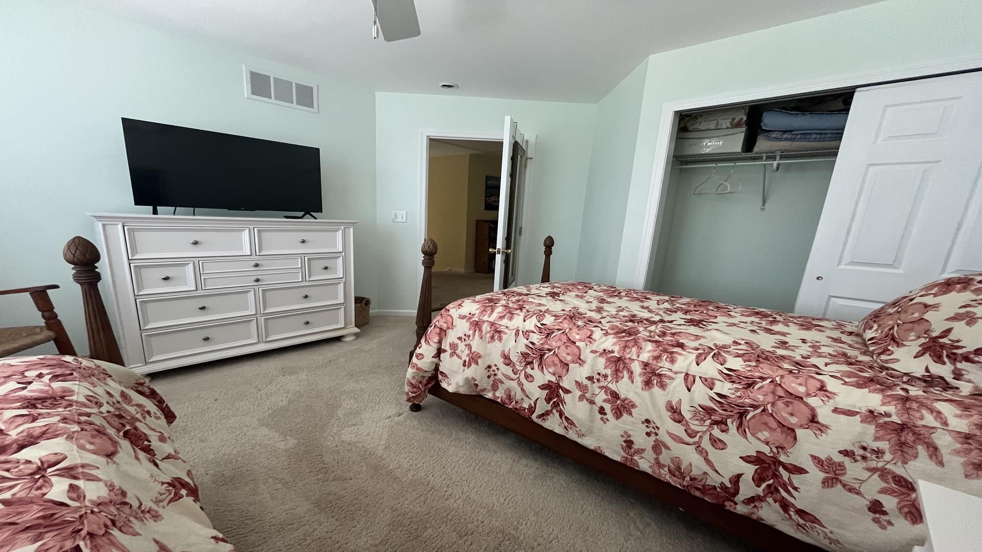 A bedroom with two beds, a dresser, a television, and a closet.