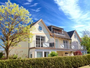 A two-story house with a balcony, large windows, and a well-maintained hedge. - Ostseeperle-3, prime location, south-facing balcony, parking space, close to the beach (Kühlungsborn)