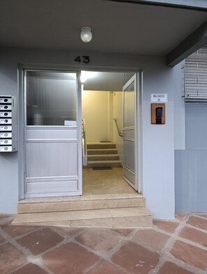 A building entrance with a door labeled '43', a security keypad, and a staircase leading inside.